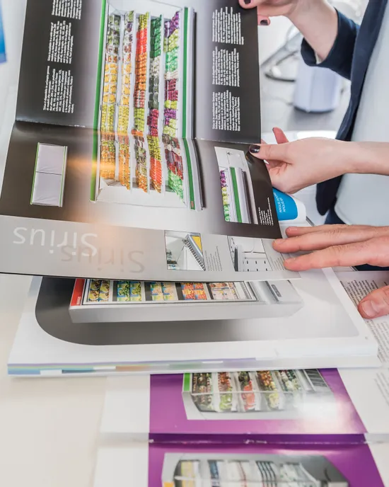 Hände blättern durch Katalogseiten mit Kühlschrankmodellen