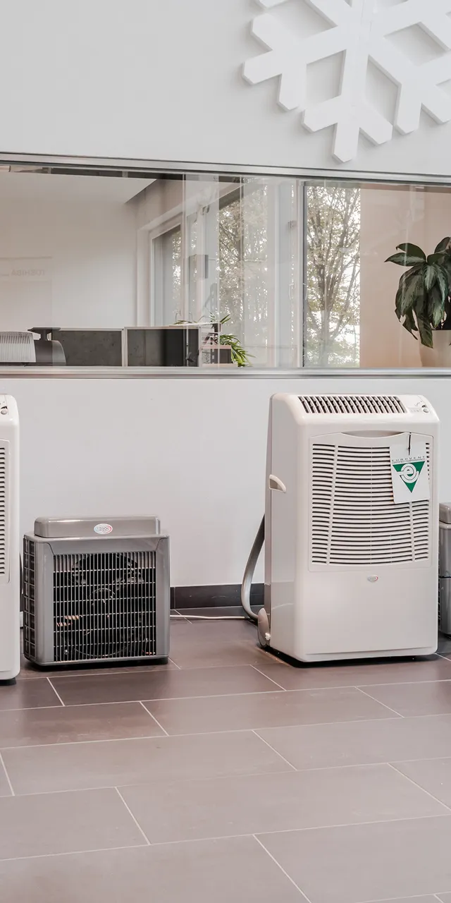 Reihe von mobilen Klimageräten im Ausstellungsraum mit großen Fenstern