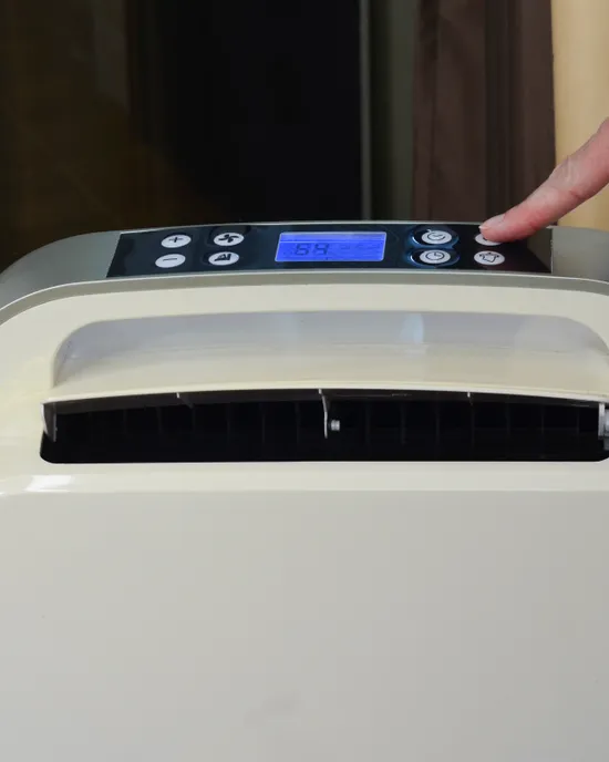 Person stellt Einstellungen des mobilen Klimageräts am Bedienfeld ein