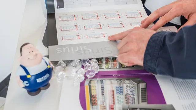 Hände blättern in Katalog mit bunten Diagrammen und einer Spielfigur an der Seite