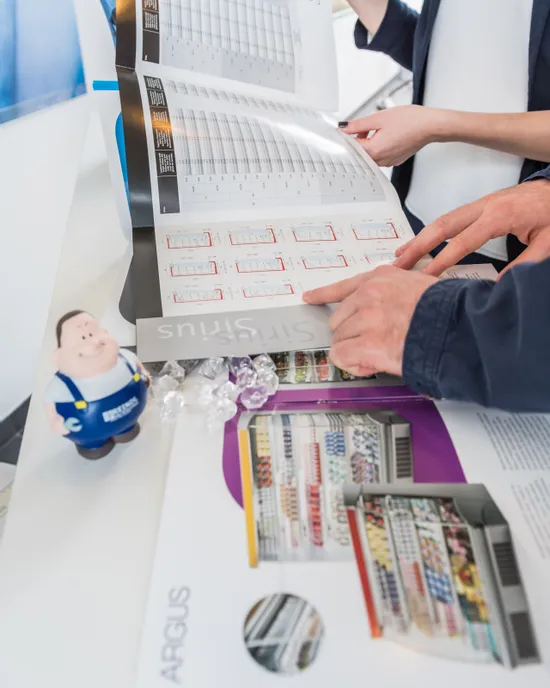 Hände blättern in Katalog mit bunten Diagrammen und einer Spielfigur an der Seite