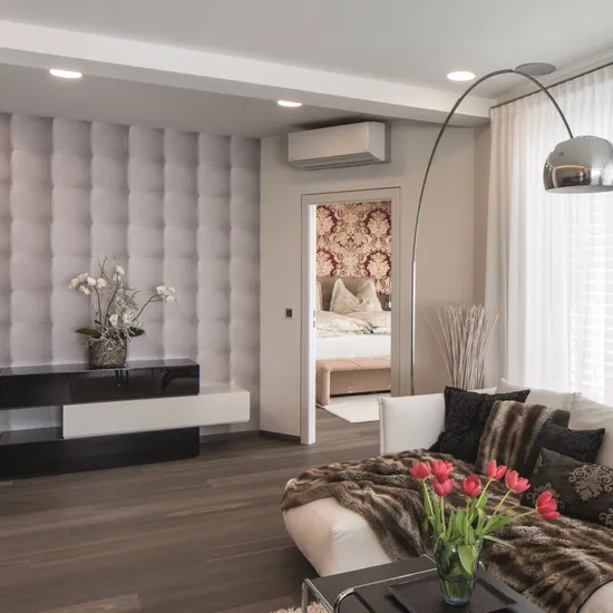 Modernes Wohnzimmer mit Tulpen auf Tisch, strukturierter Wand und Blick ins Schlafzimmer