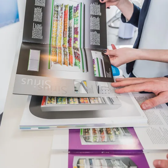 Hände blättern durch Katalogseiten mit Kühlschrankmodellen