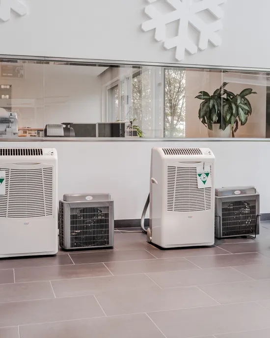 Reihe von mobilen Klimageräten im Ausstellungsraum mit großen Fenstern