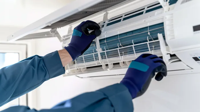 Techniker mit Handschuhen wartet eine Klimaanlage